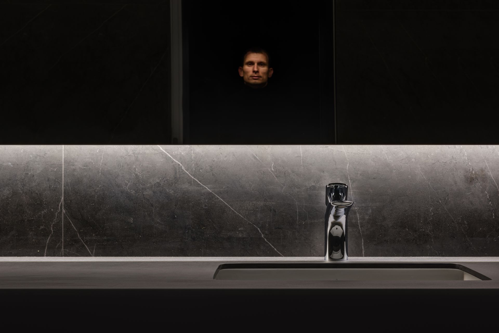 Sleek bathroom interior with marble surfaces and a reflective mirror adding to the luxurious ambiance.