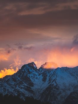 Breathtaking view of the sunset casting vibrant hues over snow-covered mountains in Lombardy, Italy.