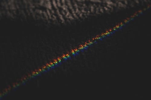 From above of rainbow ray light formed from refraction passing through prism on rug
