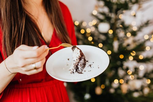 Person in Red Dress Holding White Ceramic Plate With Chocolate Cake