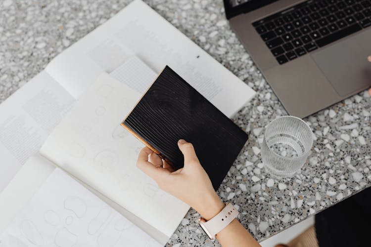 Person Holding Black Booklet