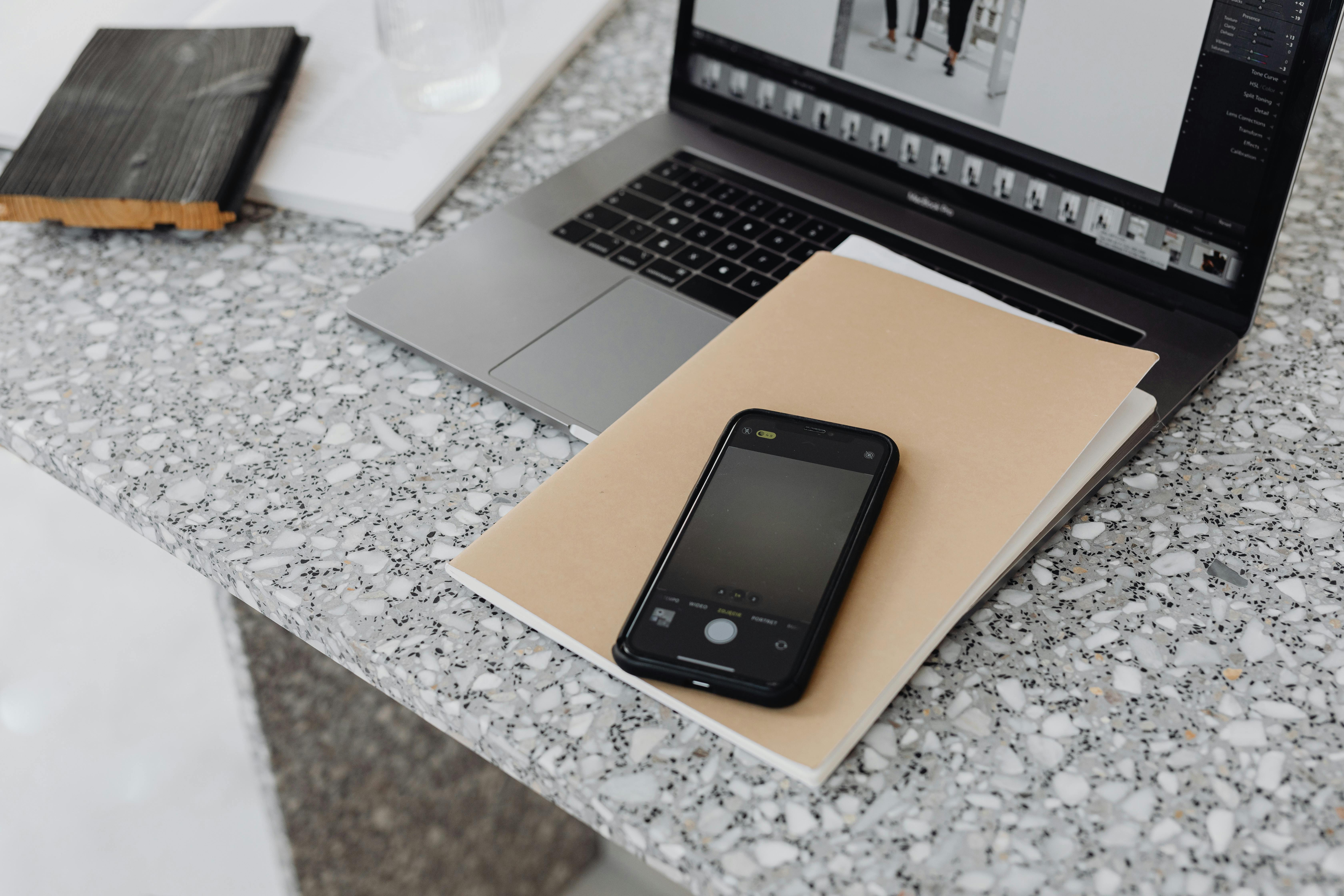 A stylish workspace featuring a laptop and smartphone on a marble surface, ideal for tech and business themes.