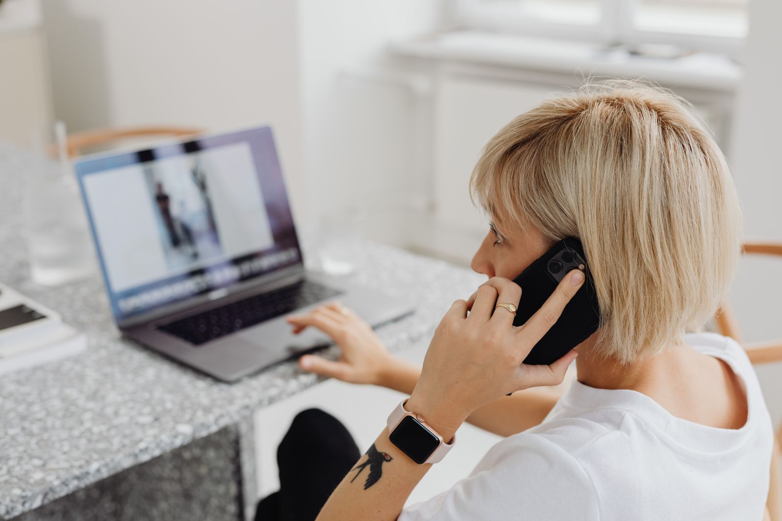 Woman working on a laptop and talking on phone indoors