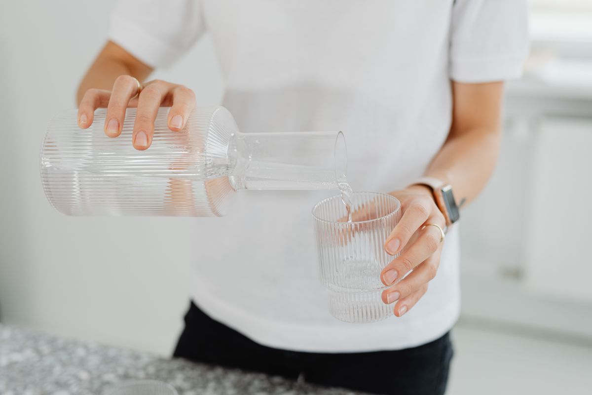 Persona sirviendo agua cristalina en un vaso