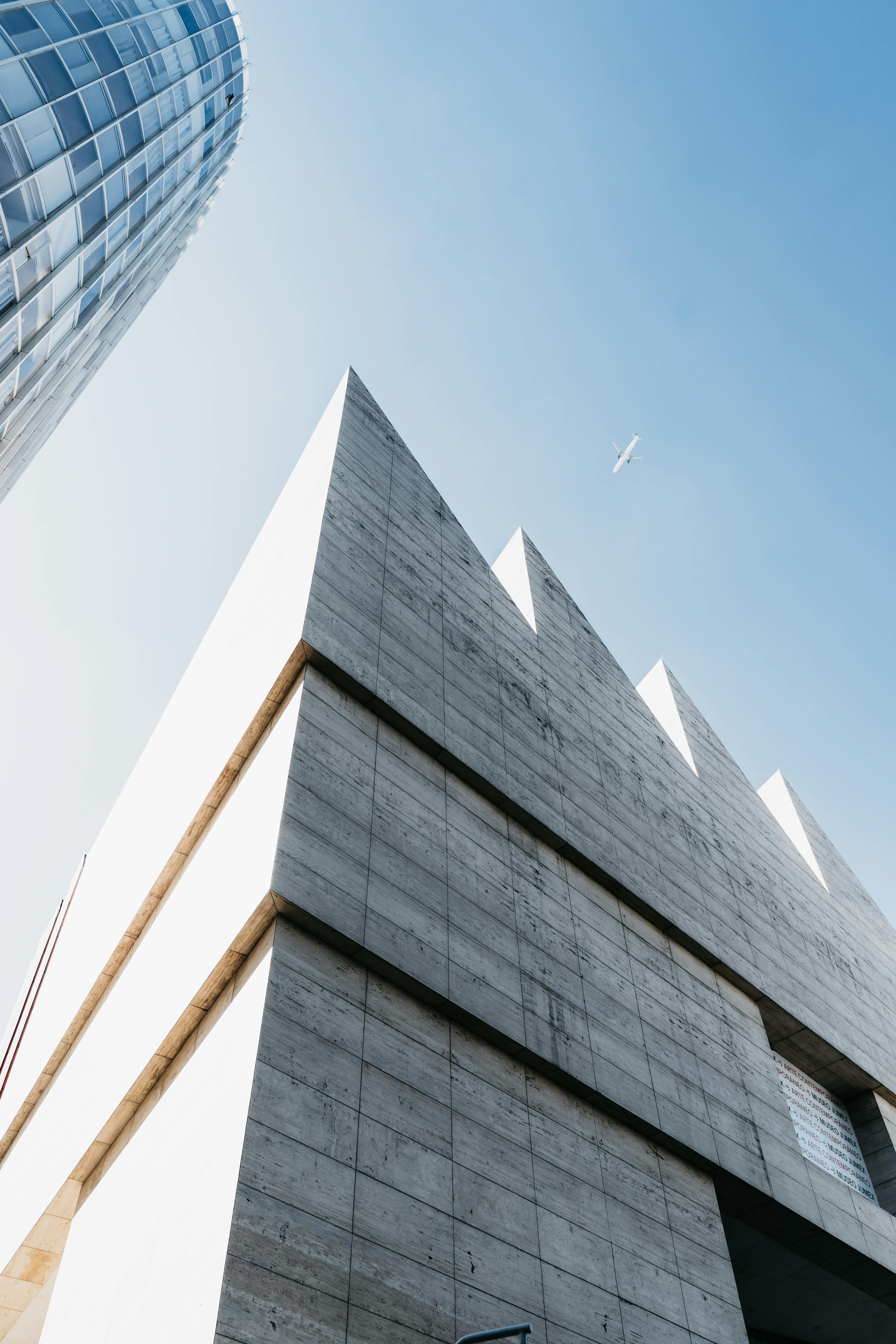From below of contemporary high rise buildings facades with geometric design under cloudless blue sky