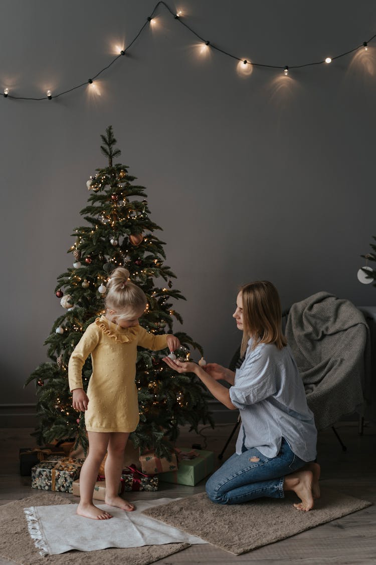 A Girl Standing On Rug Handing Over A Bauble To A Woman