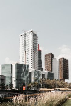 Exterior of contemporary high multistory buildings located near asphalt road under cloudy sky