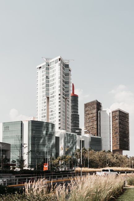 Exterior of contemporary high multistory buildings located near asphalt road under cloudy sky