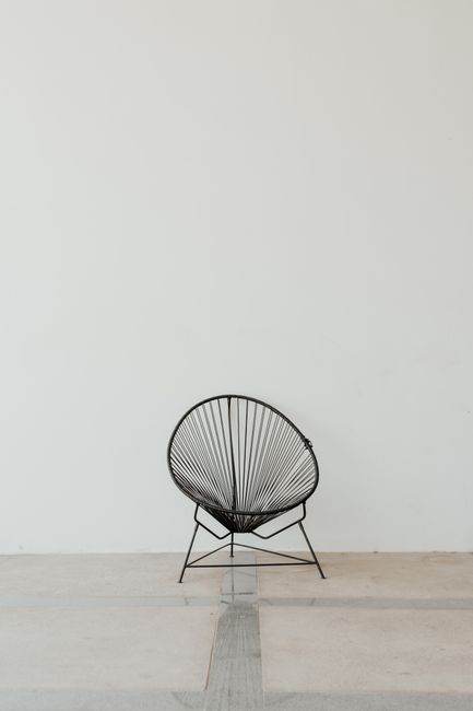 Comfortable round black Acapulco chair standing in middle of empty light spacious room