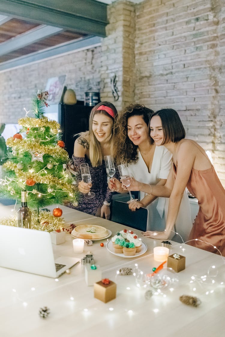 Three Women Holding Glasses Of Wine At A Zoom Party 