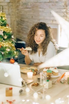 Woman with curly hair enjoying a festive virtual celebration with pie and cupcakes by a Christmas tree.