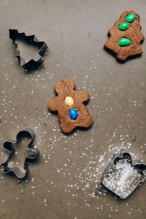 Free Gingerbread cookies with candy decorations and cookie cutters on a dark surface. Stock Photo
