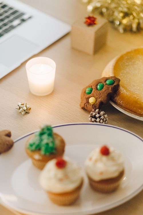 Free A warm festive dessert setting with cupcakes, cookies, and a candle, perfect for Christmas celebrations. Stock Photo