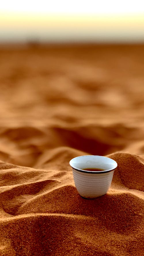 Shallow Focus of a White Ceramic Cup on Brown Sand