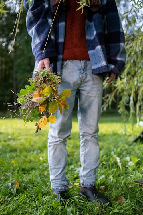 A Person Standing on the Grass Holding a Plant
