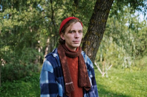 Free A man wearing a beanie, scarf, and plaid jacket outdoors during the day, set against a green background. Stock Photo