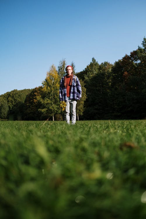 Homme En Veste Noire Et Rouge Debout Sur Le Champ D'herbe Verte