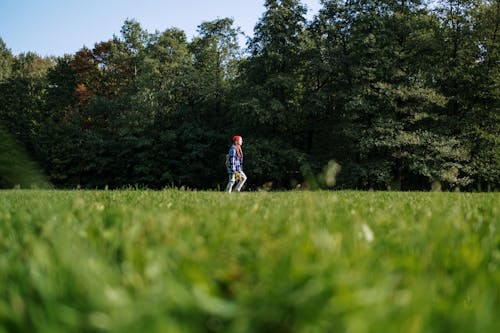 Homme En Chemise Rouge Marchant Sur Le Champ D'herbe Verte