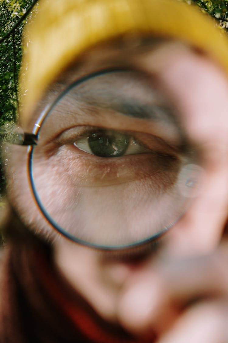 Close-up Of Man Looking Through Round Glasses Lens