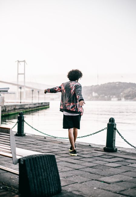 A person enjoys the serene view of Istanbul's Bosphorus Bridge on a waterfront promenade.