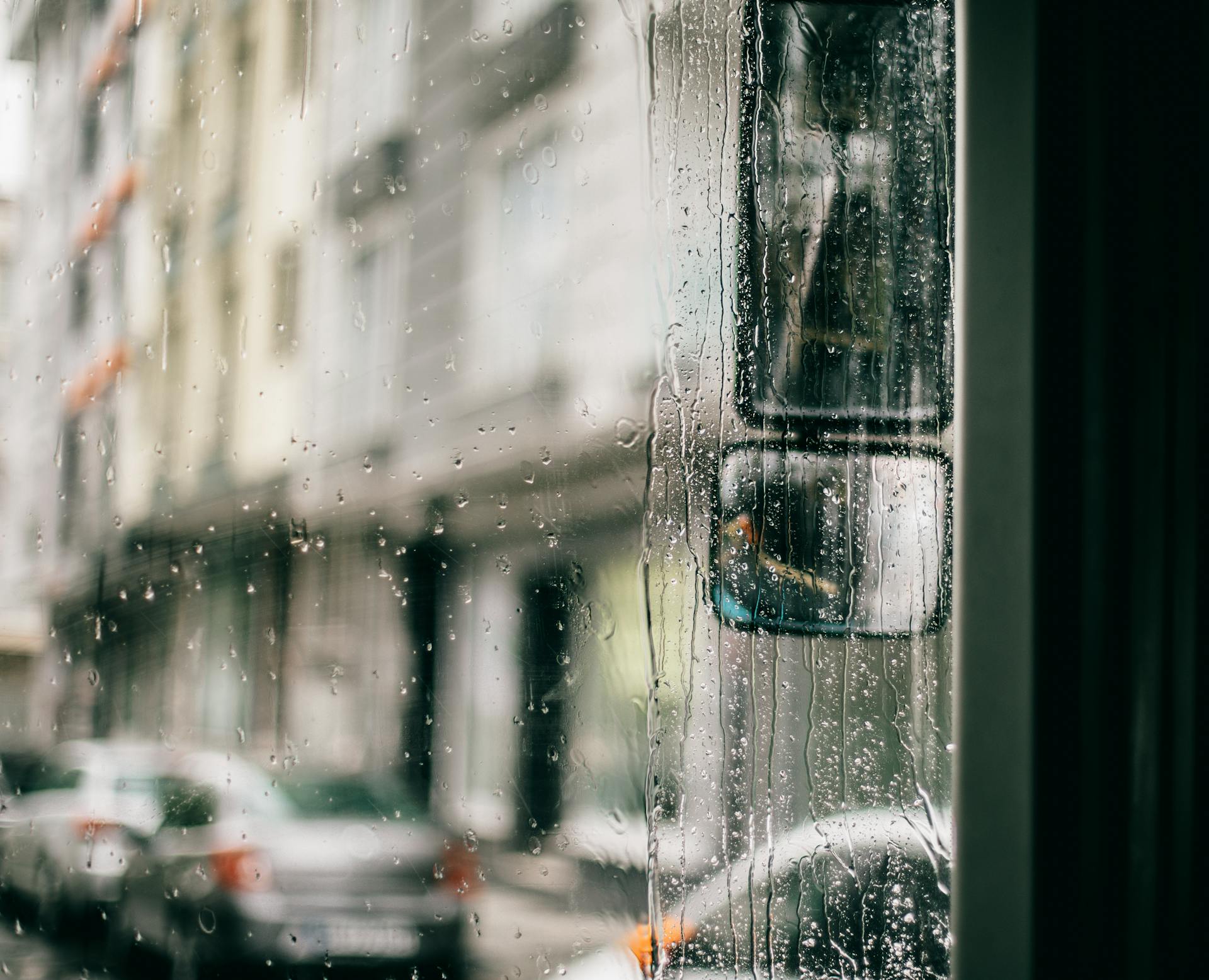Rain-soaked street view of Istanbul seen through a bus window, capturing urban life on a gloomy day.