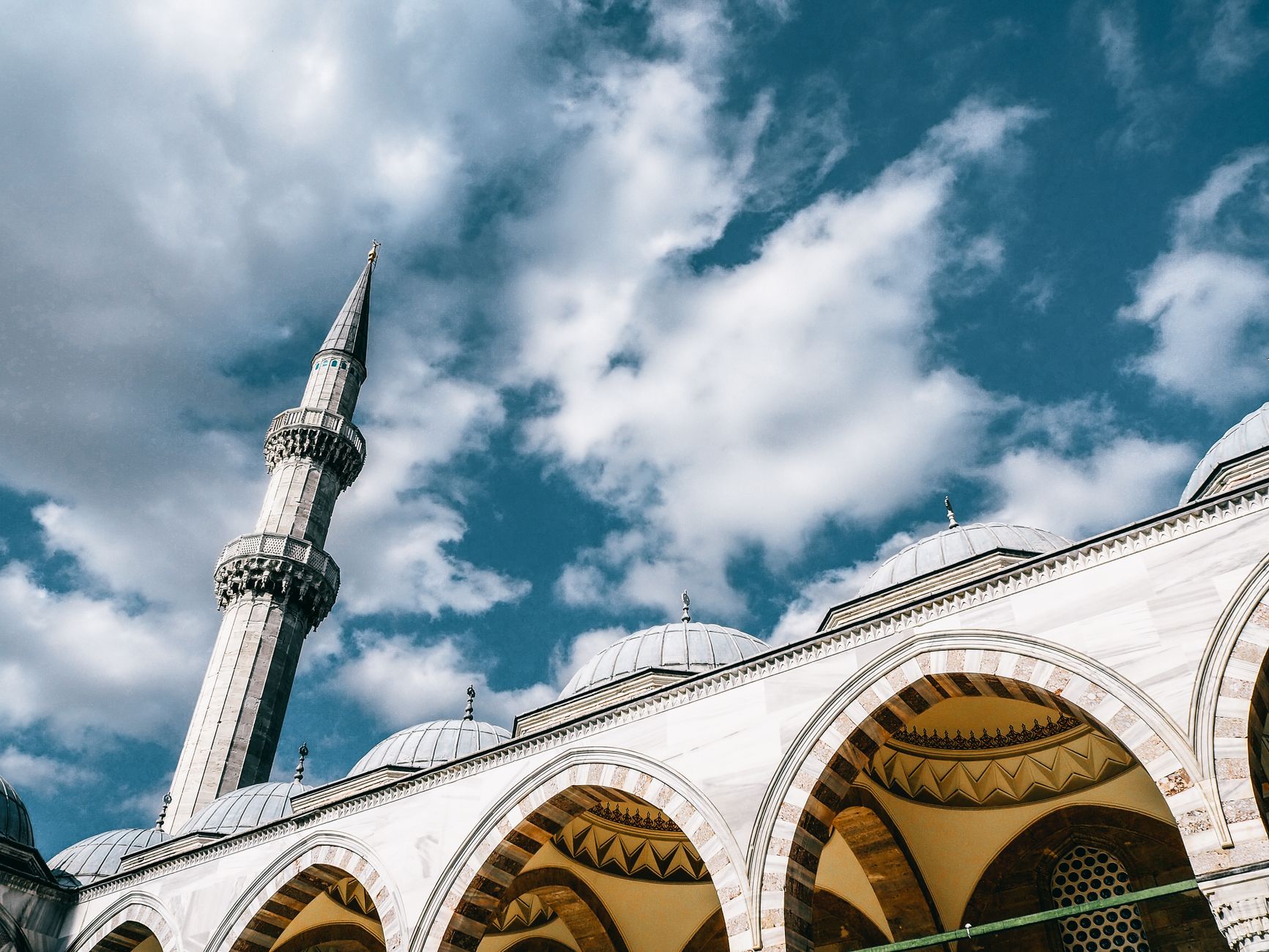 From below of famous mosque with domes and arched passages under blue cloudy sky