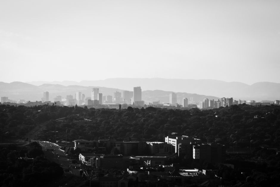 Grayscale view of Pretoria's skyline with prominent tall buildings and hills.