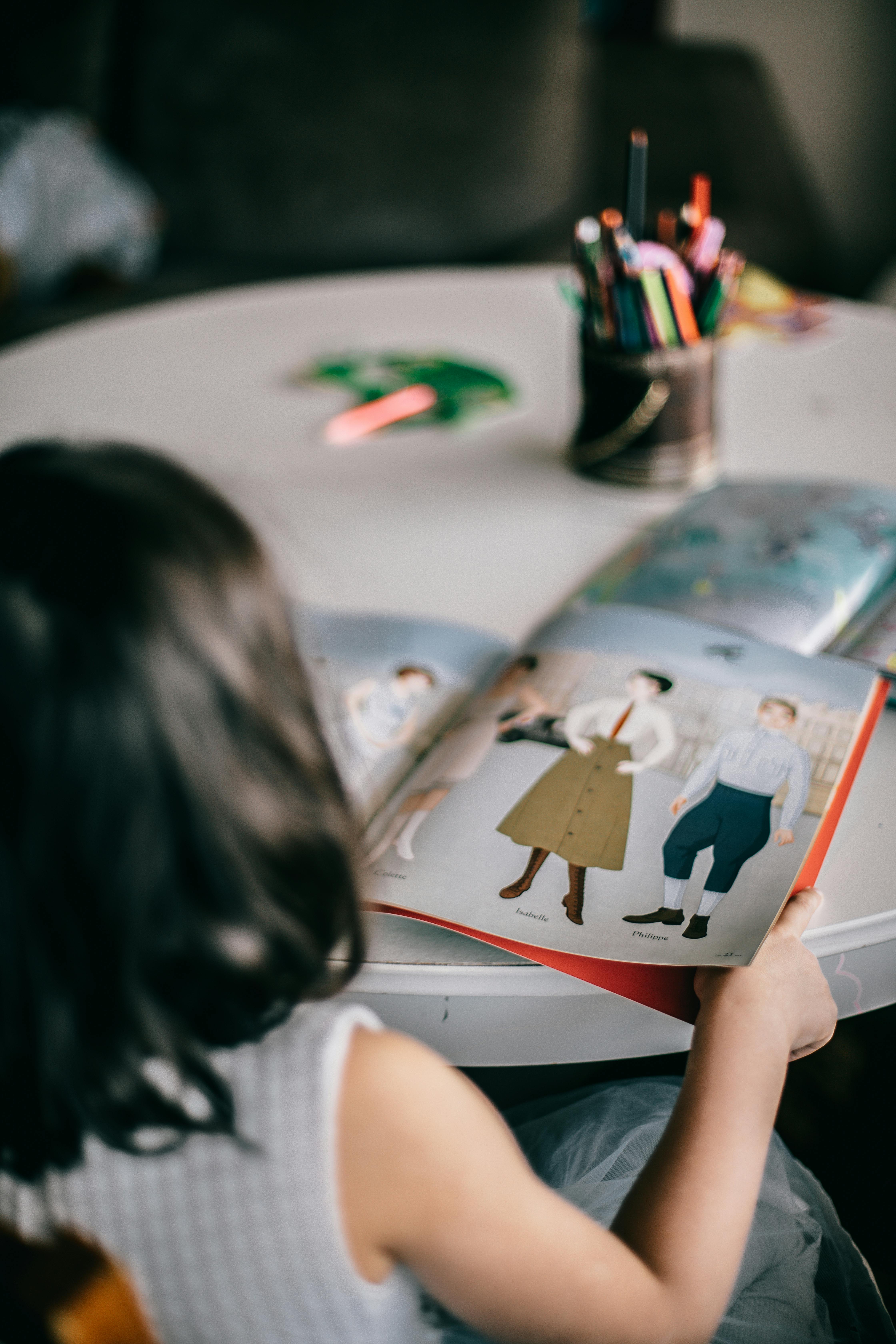 crop girl reading book at table