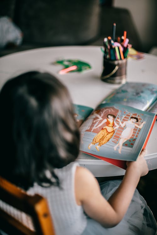 Free Anonymous girl looking at picture in book Stock Photo