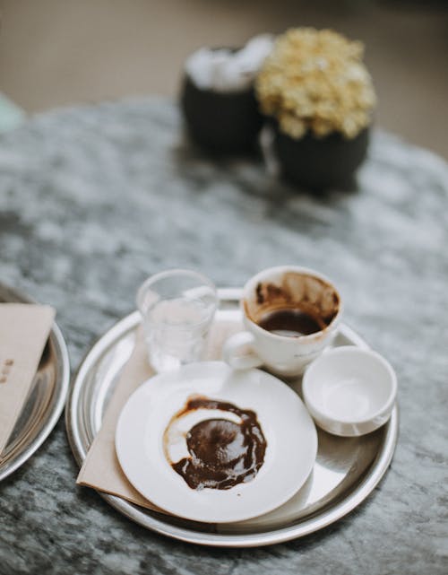 From above of hot chocolate served near plate on metal tray on blurred background