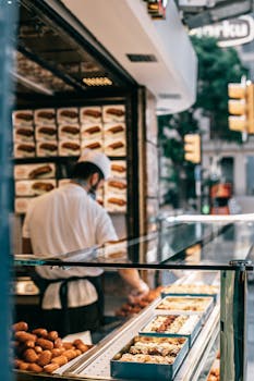 A baker arranges pastries at a street shop in Istanbul, showcasing various baked goods.