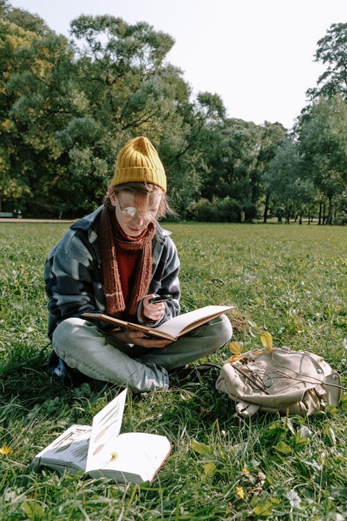 Woman in Brown Scarf Sitting on Green Grass Field