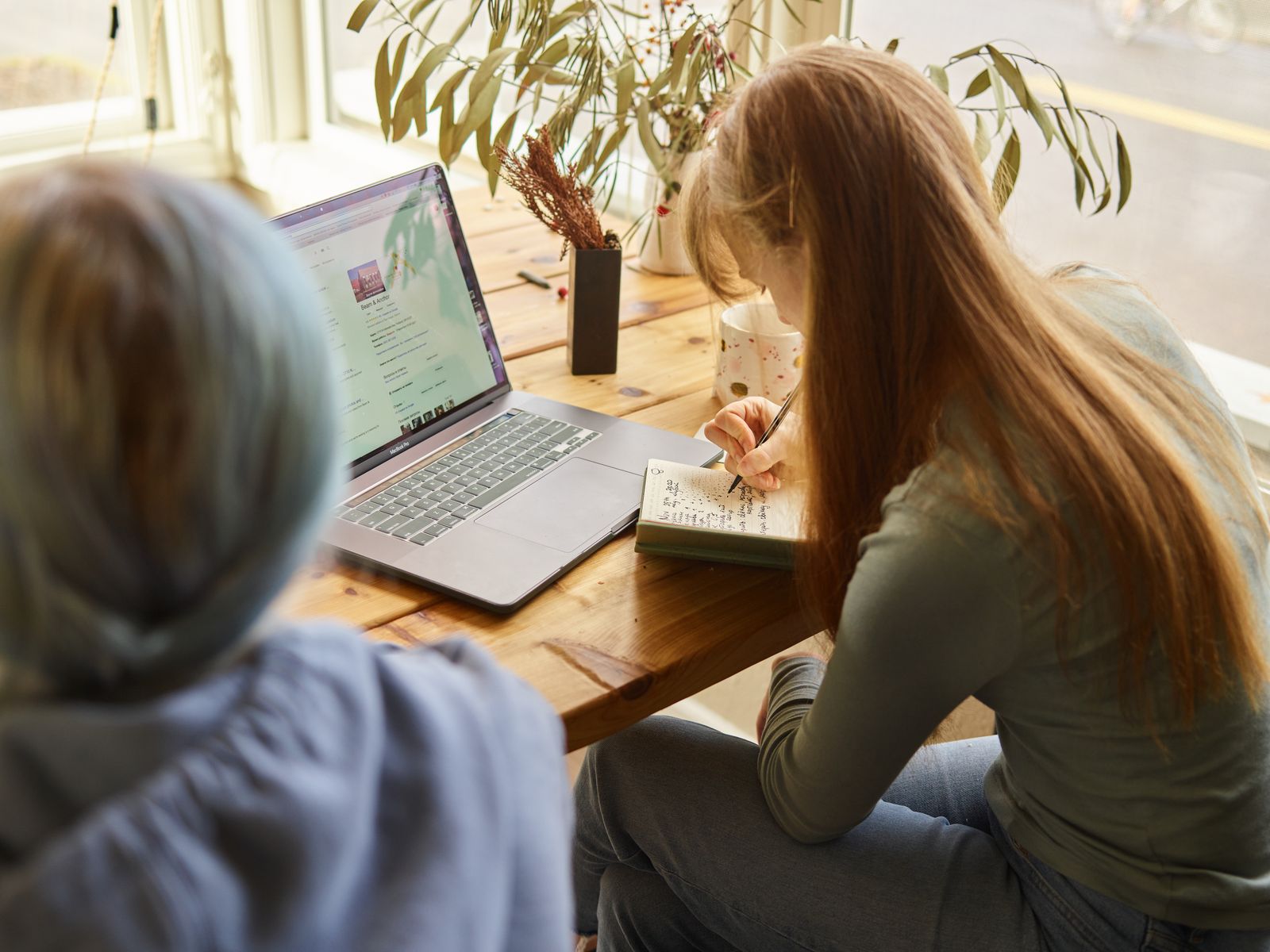 Étudiante prenant des notes pendant une recherche sur ordinateur portable