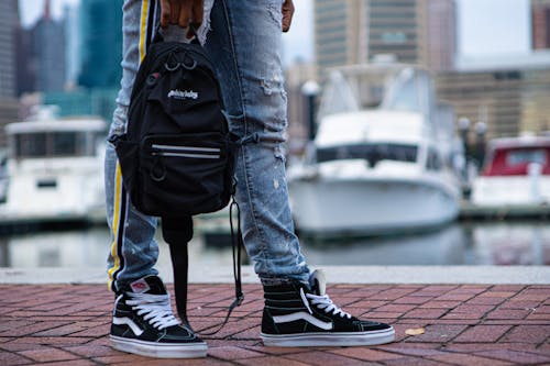 A Person in Blue Denim Jeans and Black and White Sneakers