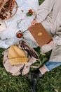 Person in White Jacket and Blue Denim Jeans Sitting on White Textile With Brown Paper Bag
