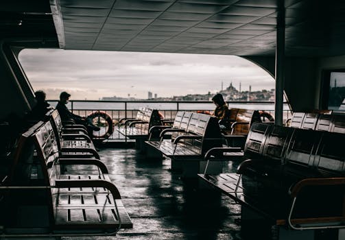 Istanbul ferry interior with passengers and city skyline view, capturing a moody ambiance.