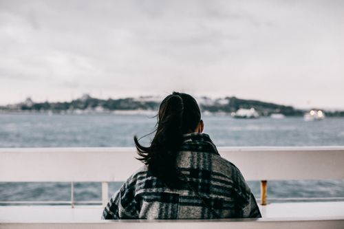 Free Woman in plaid jacket enjoying serene sea view, capturing tranquility in Istanbul. Stock Photo