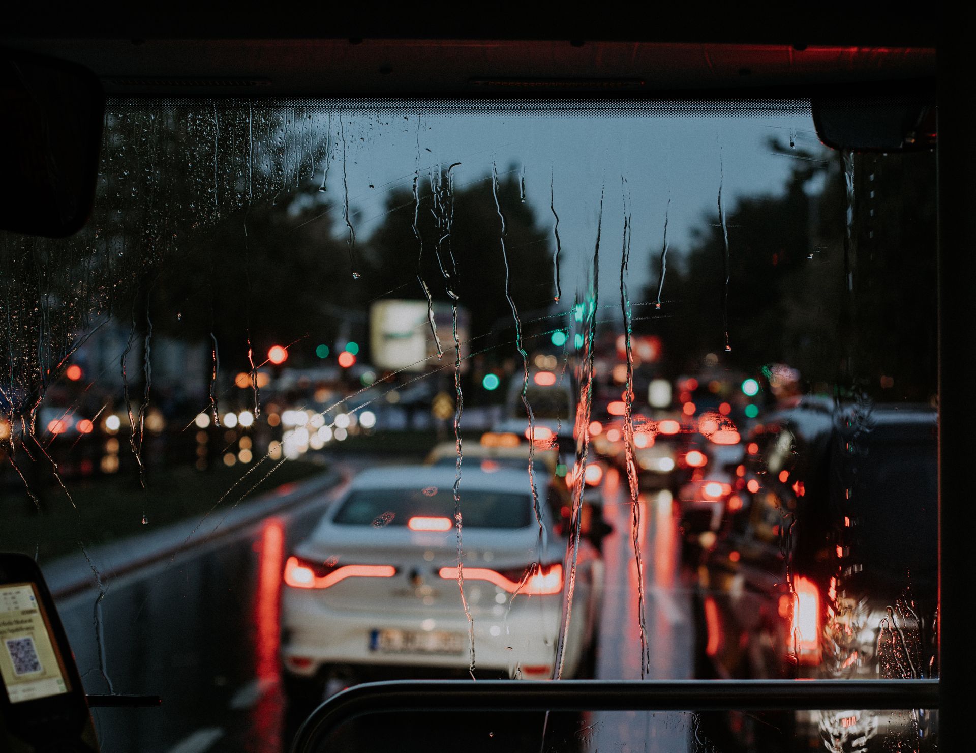 A blurred view of street traffic through a rain-soaked window at night, capturing city lights and vehicles.