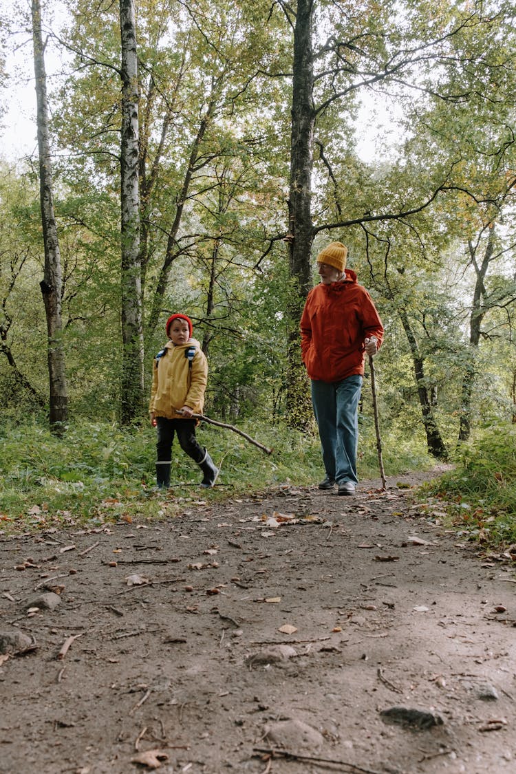 An Elderly Man And A Young Boy Walking Together In Forest