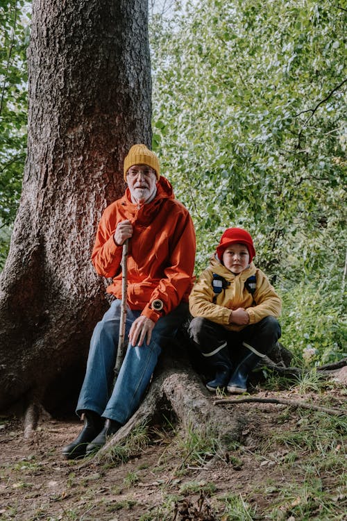 Man and Kid Sitting Beside the Brown Tree Trunk