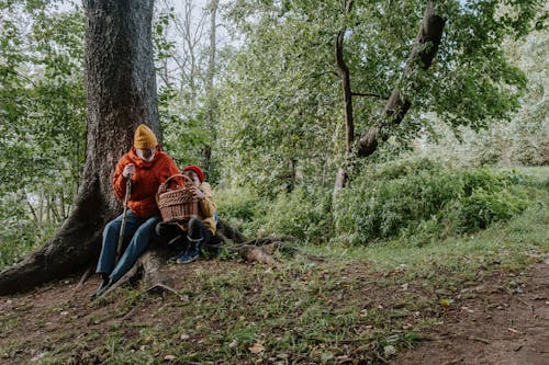 A Man and Kid Sitting Beside the Brown Tree Trunk