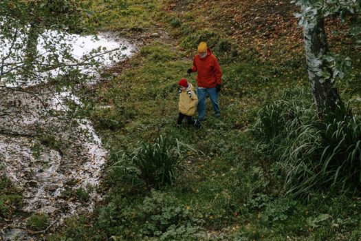 Boy in Red Hoodie and Blue Pants Walking on Green Grass Field