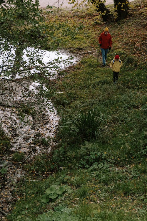 A Man and His Grandson Walking in Green Grass near the Lake 
