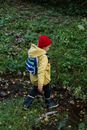 Boy in Yellow Hoodie and Blue Denim Jeans Standing on Green Grass Field