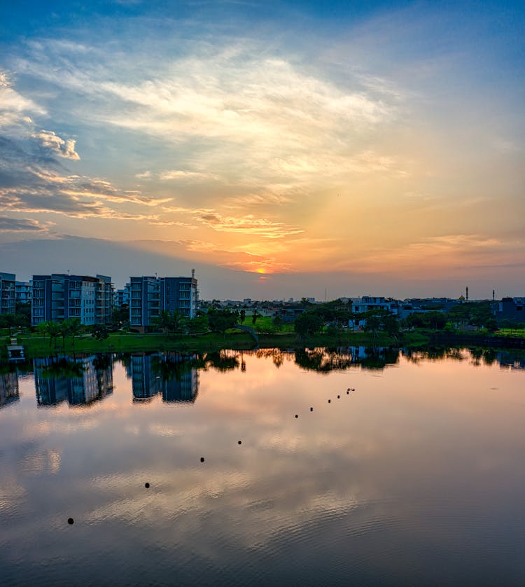 Calm Lake In Residential District Under Colorful Sky At Sunset