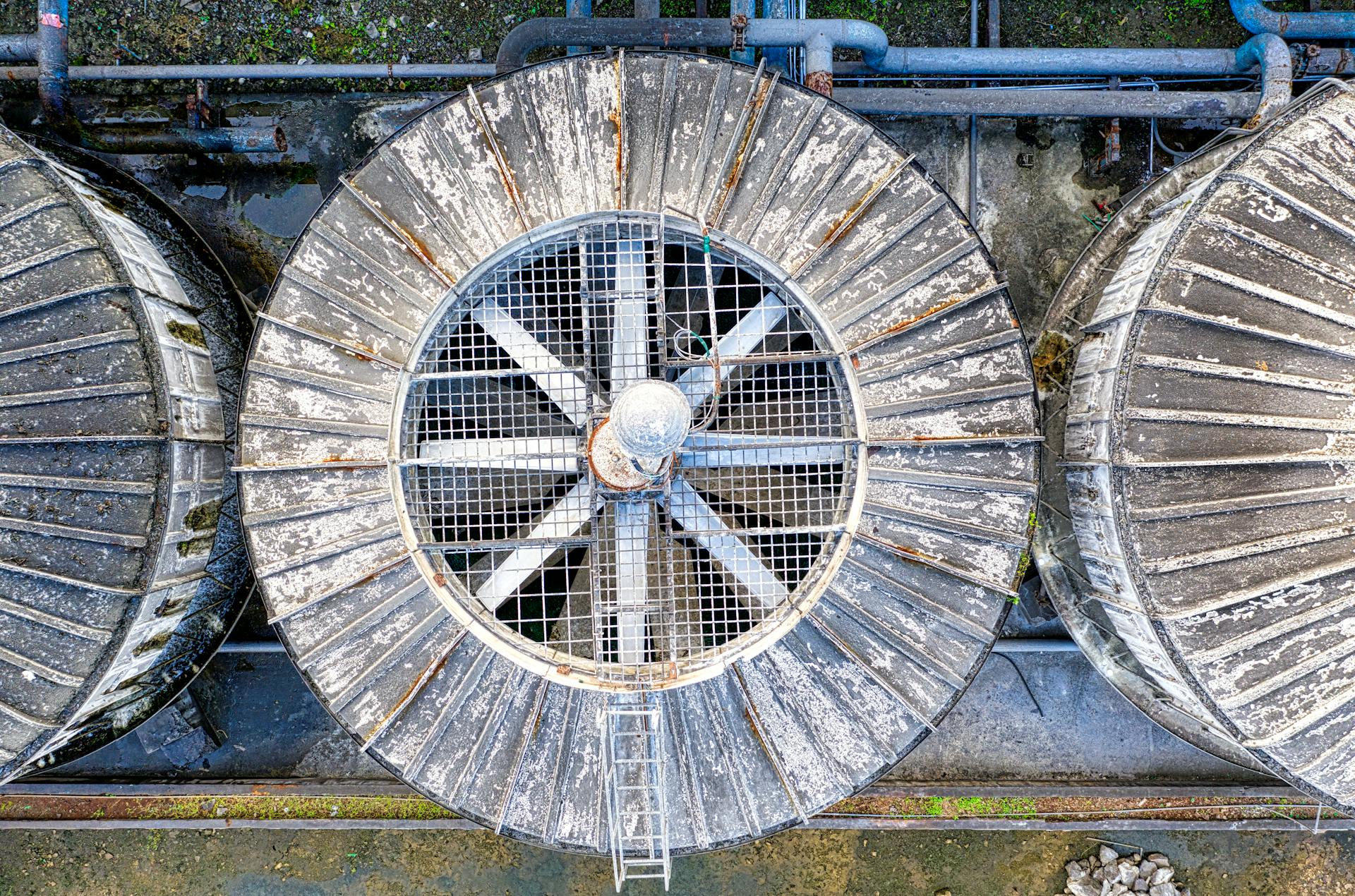 Drone top view of big shabby old metal ventilation fans on factory among pipes