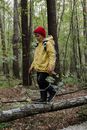 Man in Yellow Jacket and Black Pants Standing on Tree Log