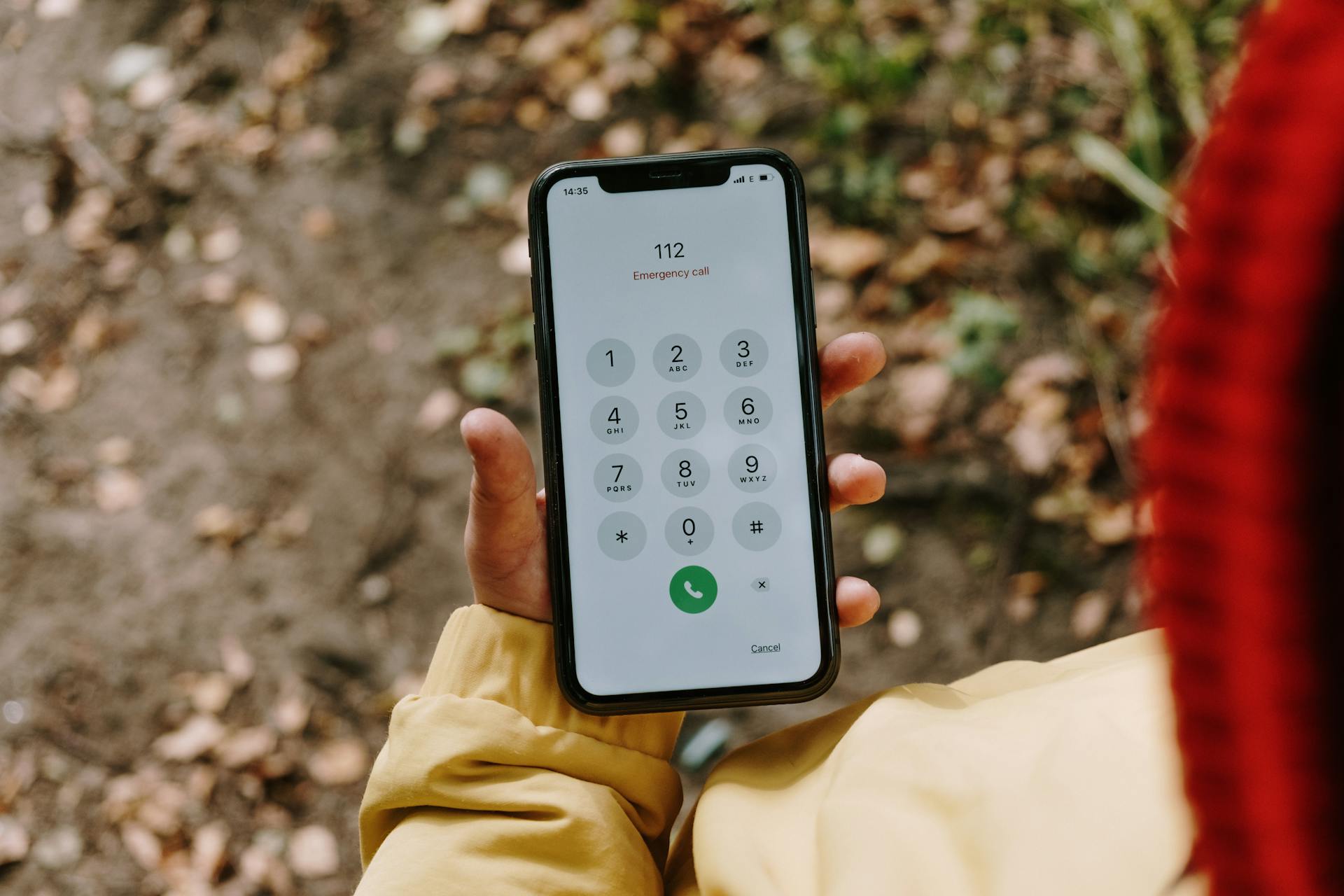 Close-up of a smartphone displaying emergency number 112 outdoors.