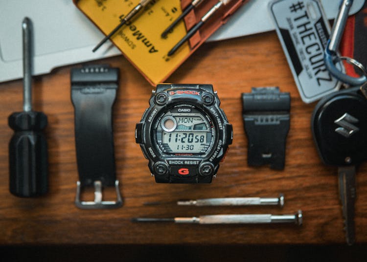 A Broken Wristwatch And Tools On A Wooden Surface