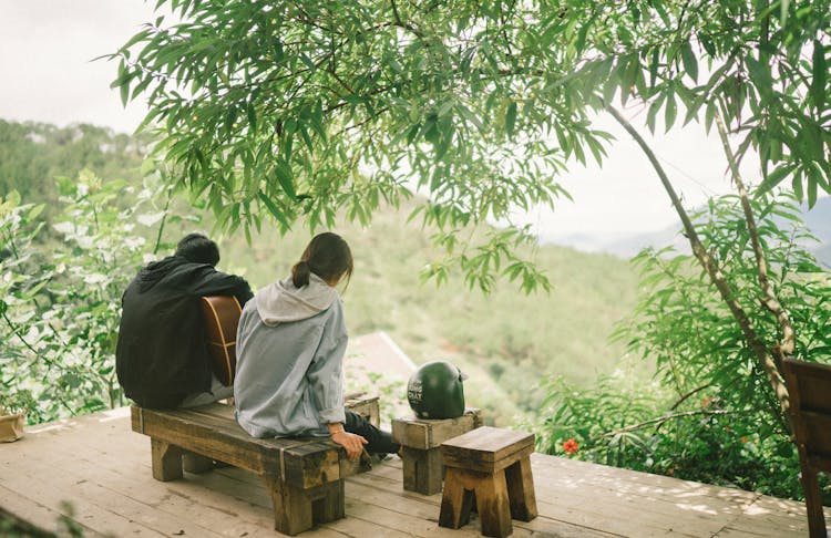 Couple Sitting On Bench In Green Garden